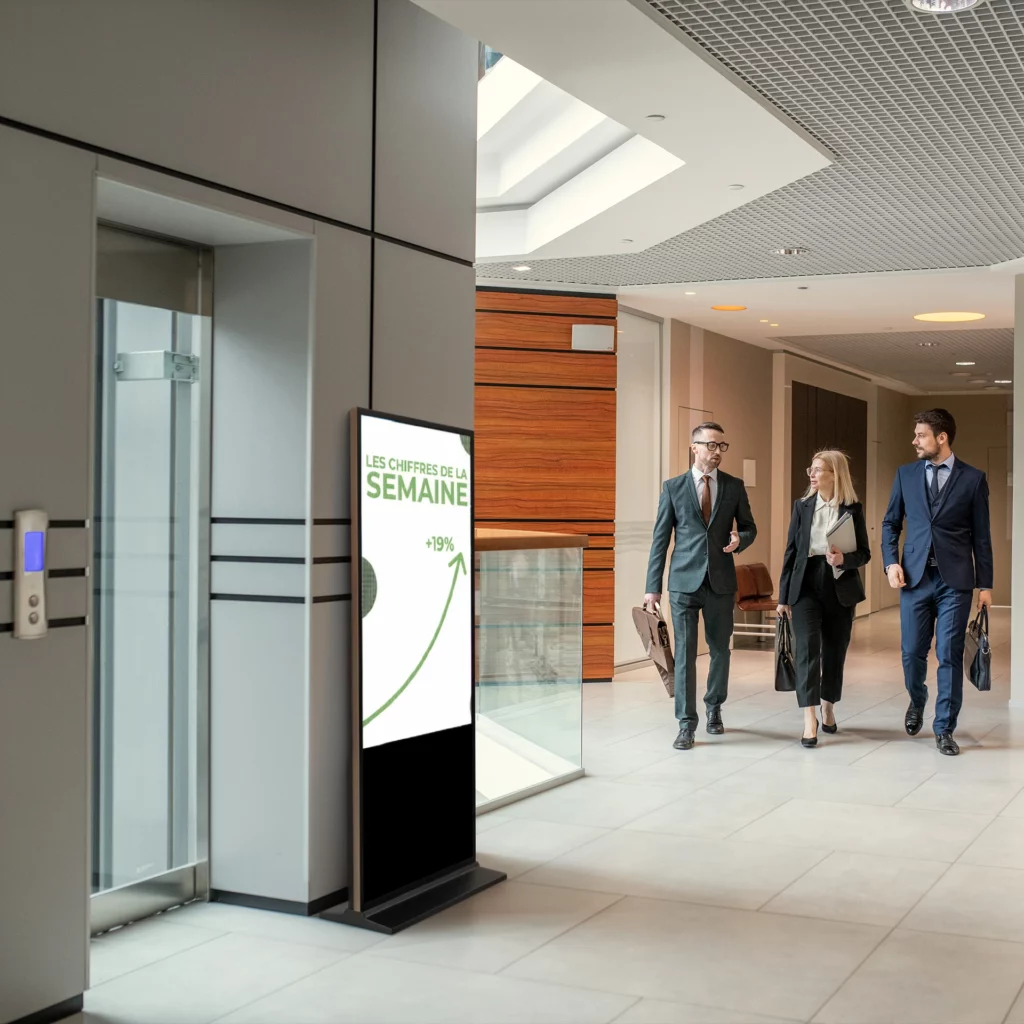 totem numérique placé dans un couloir d'entreprise qui affiche les derniers chiffre du mois